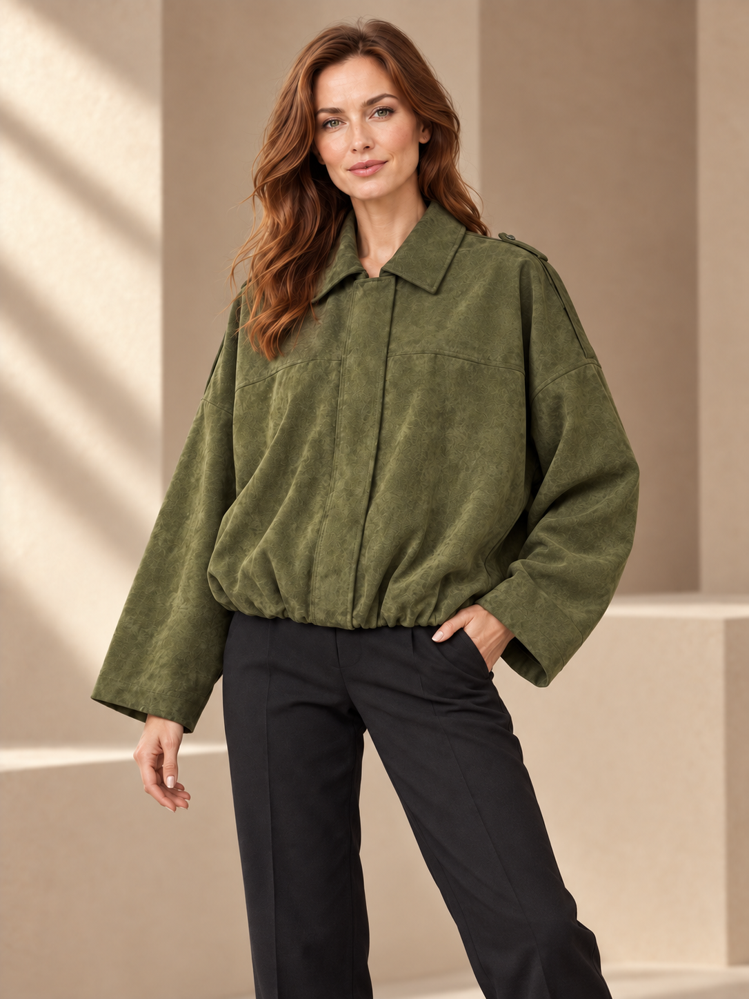 JXR1001 suede-effect pilot jacket in medium khaki on a female model in a sporty relaxed pose, warm beige studio
